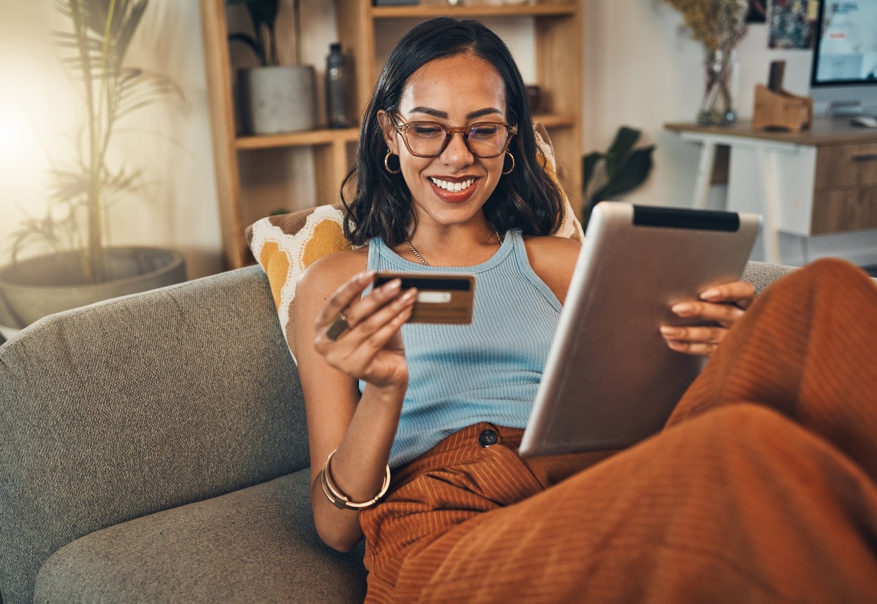 Une jeune fille heureuse avec sa carte de crédit devant son iPad