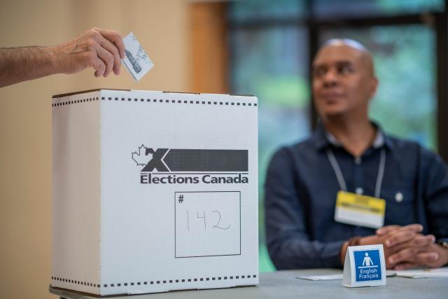 Une main dépose un bulletin de vote dans une urne à l'occation d'une élection au Canada
